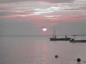 Black, white and red picture of boats on the ocean in Jamaica at sunset